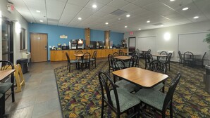 A spacious indoor area with multiple tables and chairs, a coffee station, and a patterned carpet. - Days Inn by Wyndham Sidney NE (Sidney)