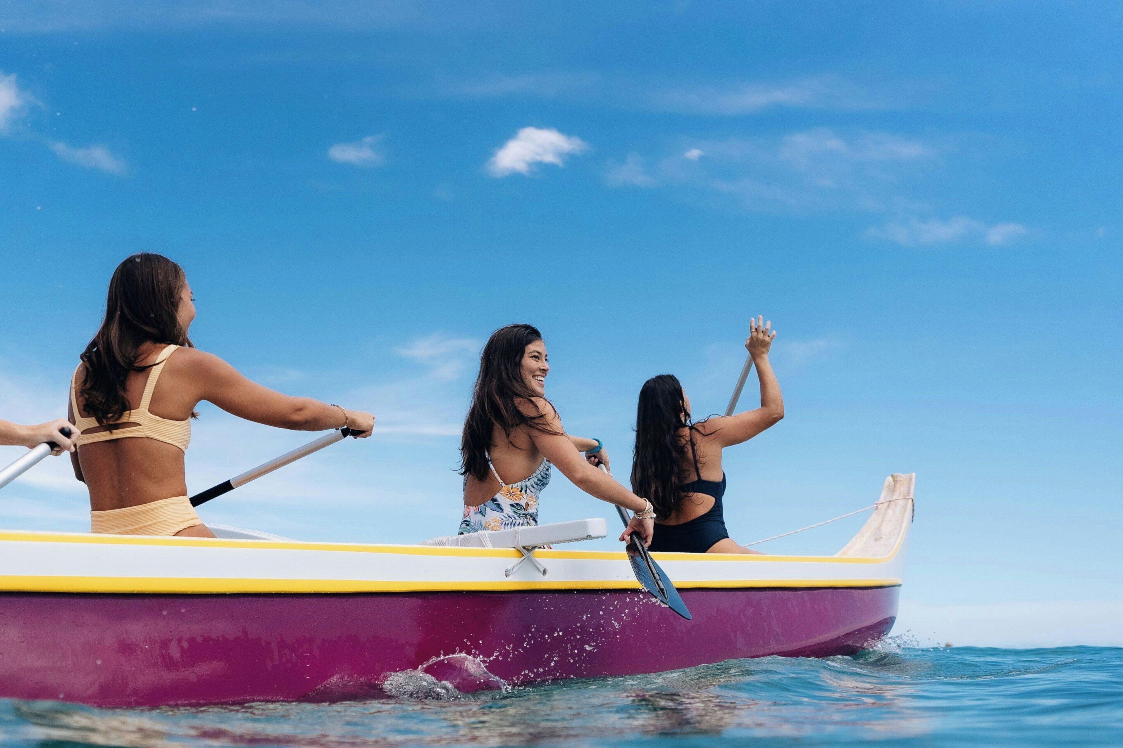 Tres personas remando en un bote pequeño sobre el agua.