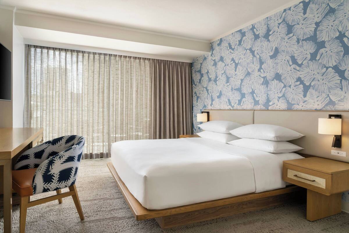 A hotel room with a large bed, a desk, and a chair.