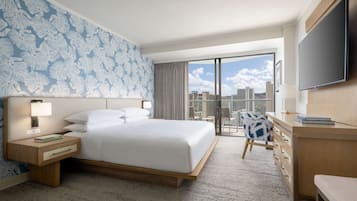A hotel room with a large bed, a desk, a chair, a TV, and a balcony with a city view.