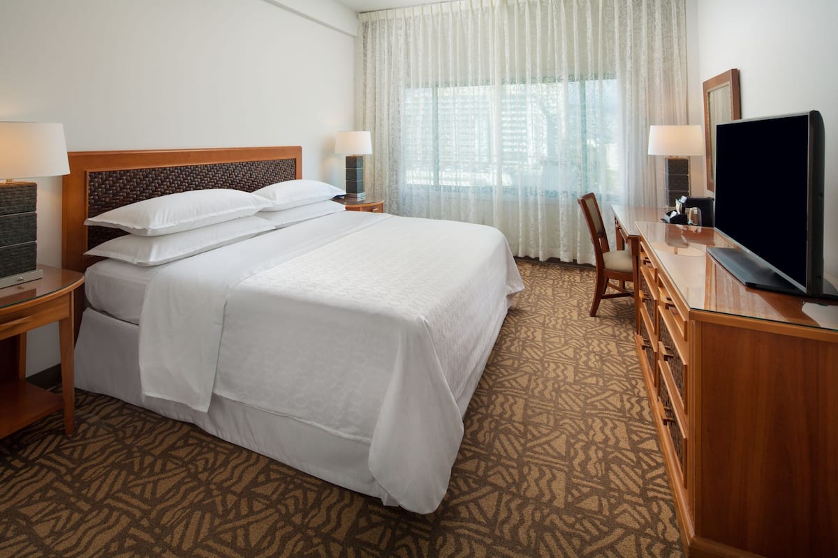 Una habitación de hotel con una cama grande, televisor, escritorio y una silla.