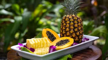 Une assiette contenant des tranches d’ananas, de papaye et de banane, posée sur une table en bois.