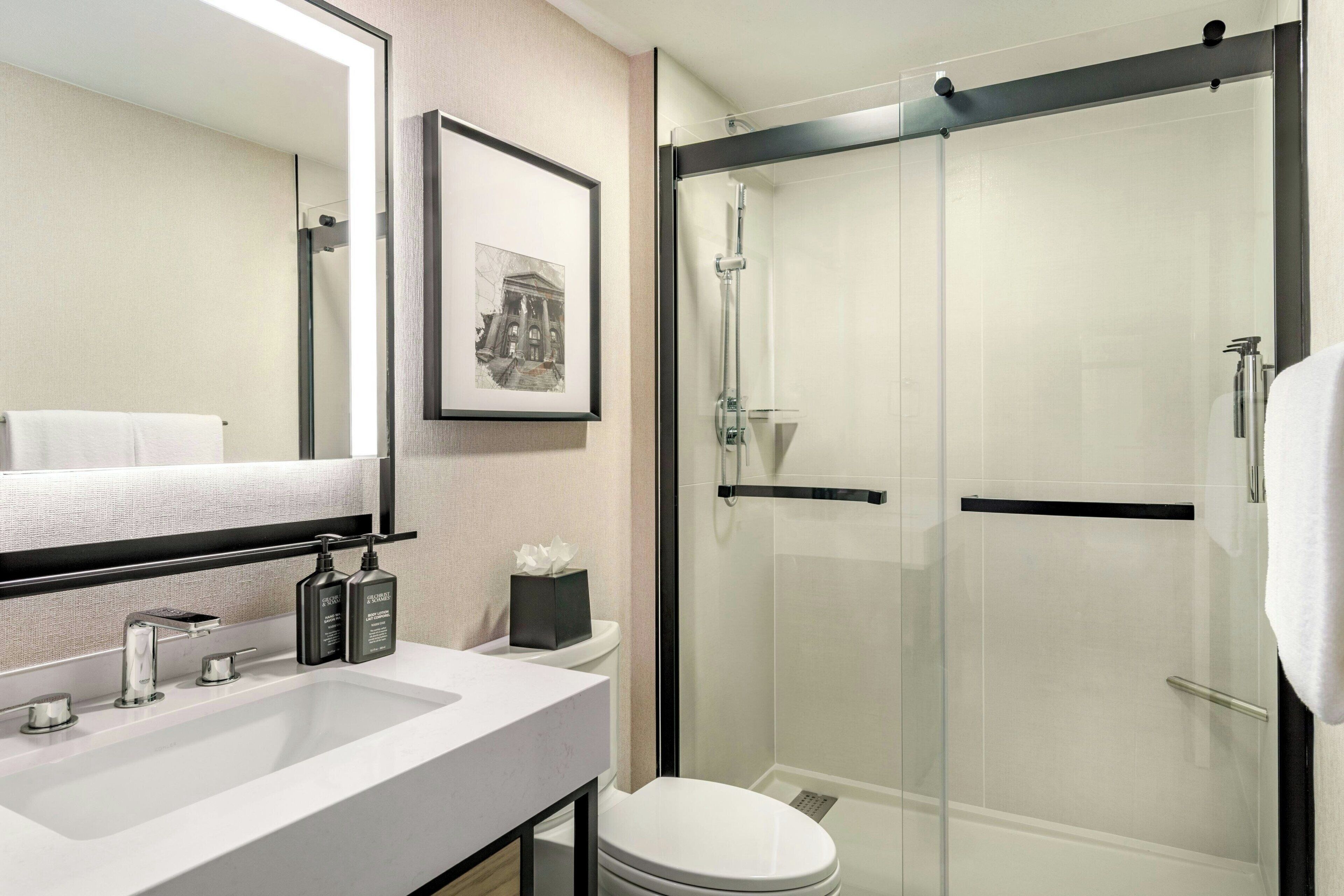 A modern bathroom with a white sink, a toilet, and a glass-enclosed shower.