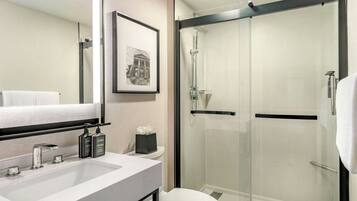 A modern bathroom with a white sink, a toilet, and a glass-enclosed shower.