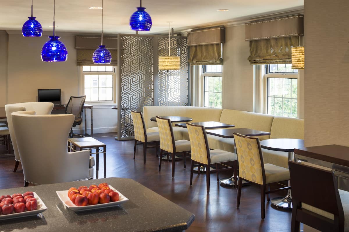 A hotel lobby with seating arrangements, a buffet table with fruit, and decorative lighting.