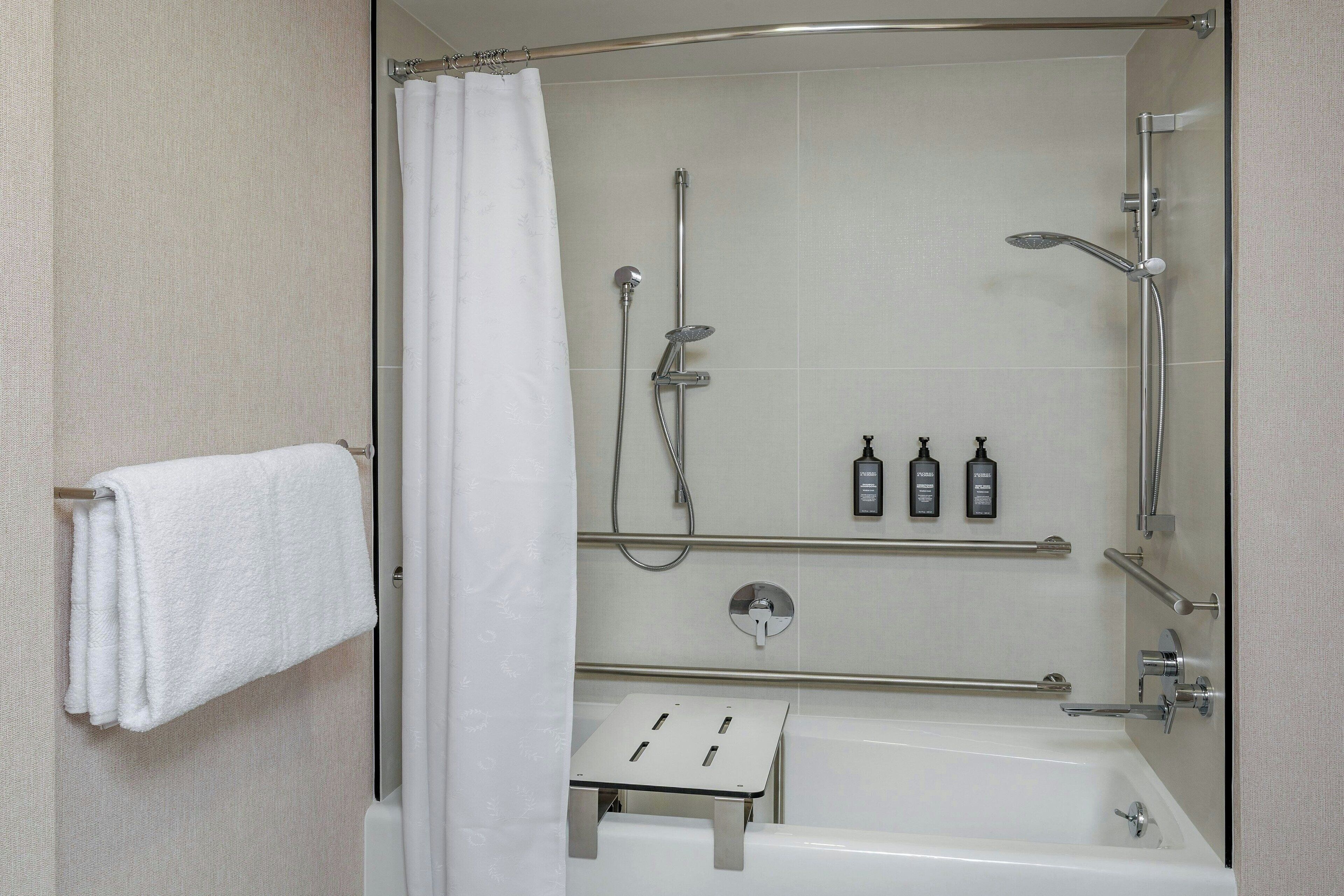 Un bany modern amb una cabina de dutxa de vidre, una banyera blanca i un suport per a tovalloles.