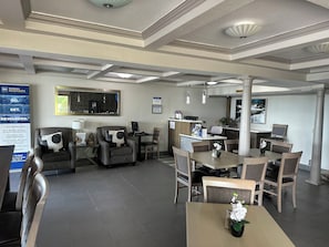 A hotel lobby with a reception desk, seating area, and a dining table with chairs.