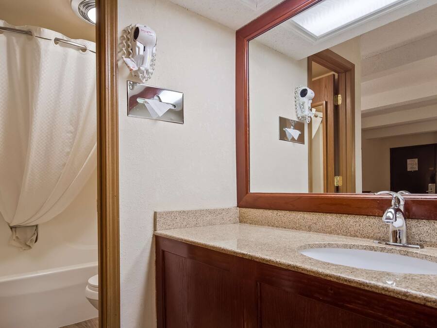 A bathroom with a sink, mirror, and shower curtain.