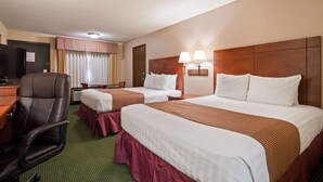 Ein Hotelzimmer mit zwei Betten, einem Schreibtisch mit Stuhl, einem Fernseher und einem Fenster mit Vorhängen.