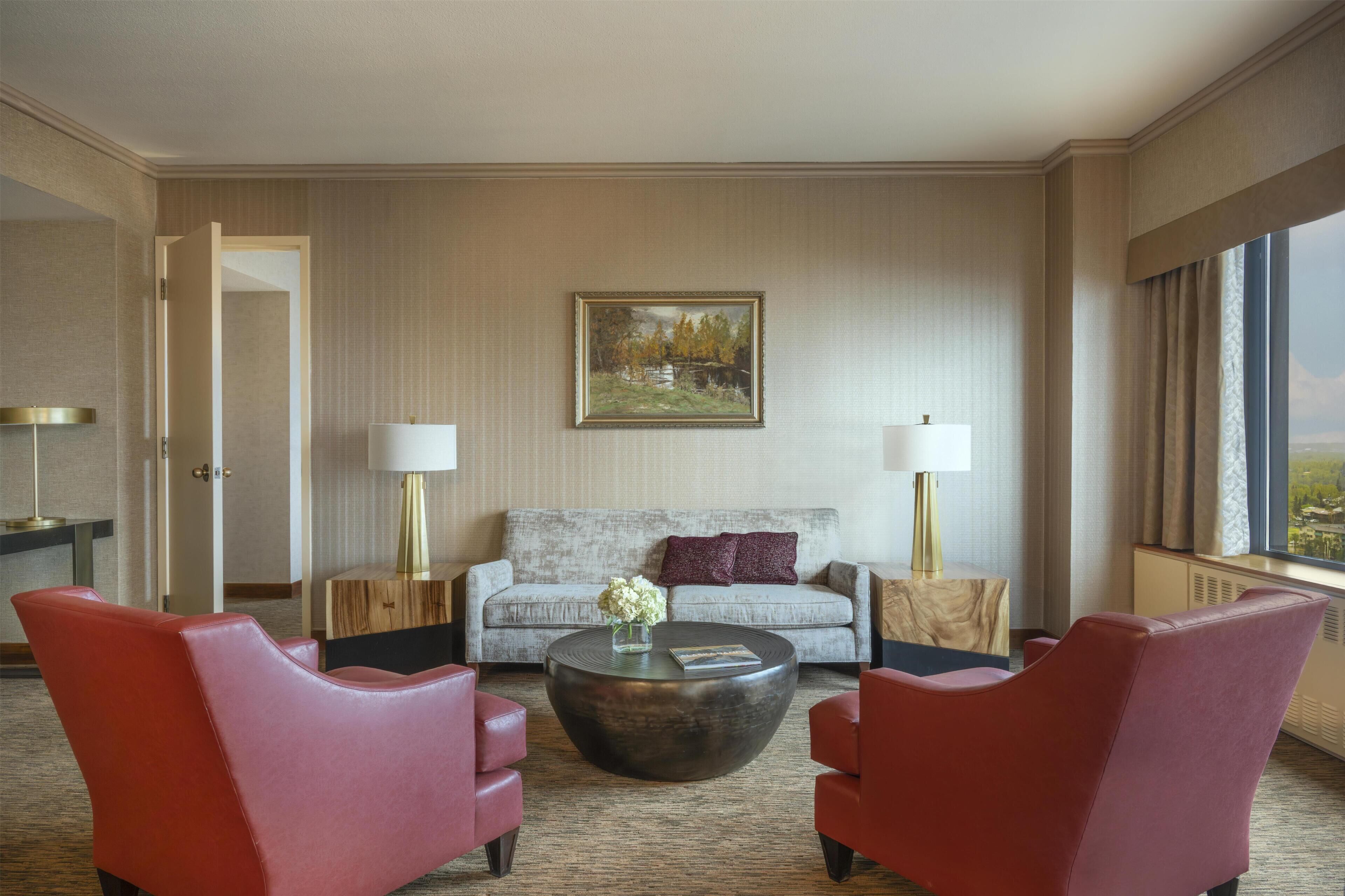 Habitación de hotel con un sofá, dos sillones, una mesita de centro y un cuadro en la pared.