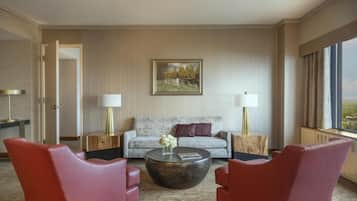 Habitación de hotel con un sofá, dos sillones, una mesita de centro y un cuadro en la pared.