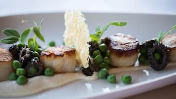 A plated dish with seared scallops, pea puree, and a creamy sauce.