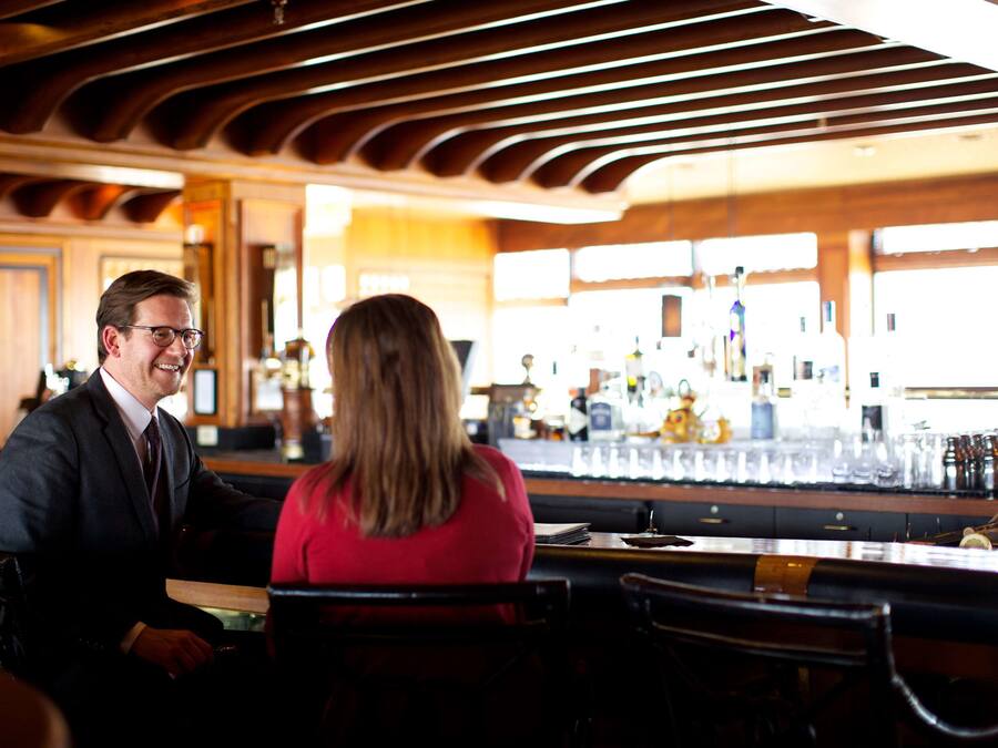 A bar area with wooden ceiling, bar counter, and seating.