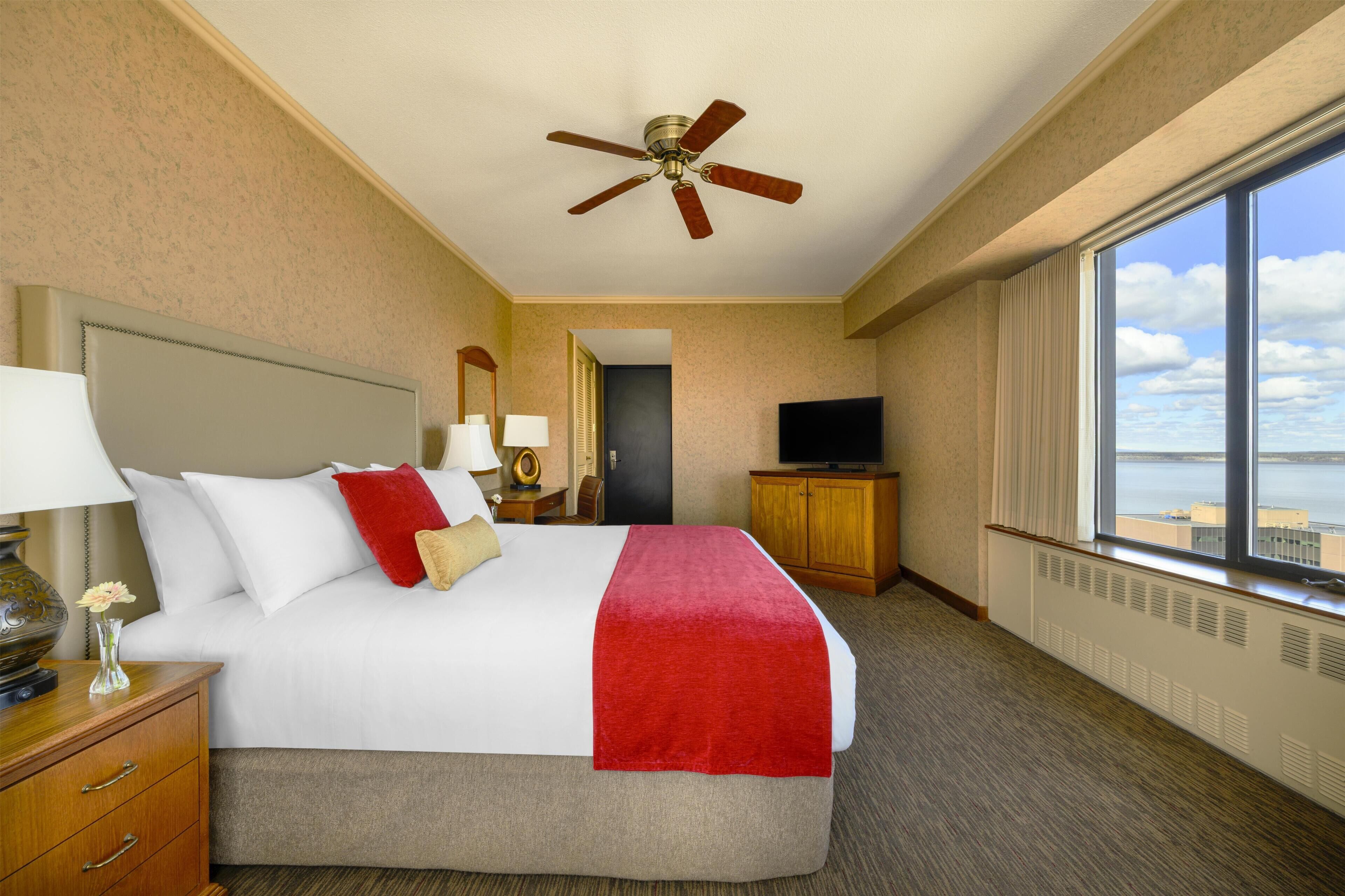 Une chambre d’hôtel avec un lit, un bureau, une télévision et une vue sur la ville.
