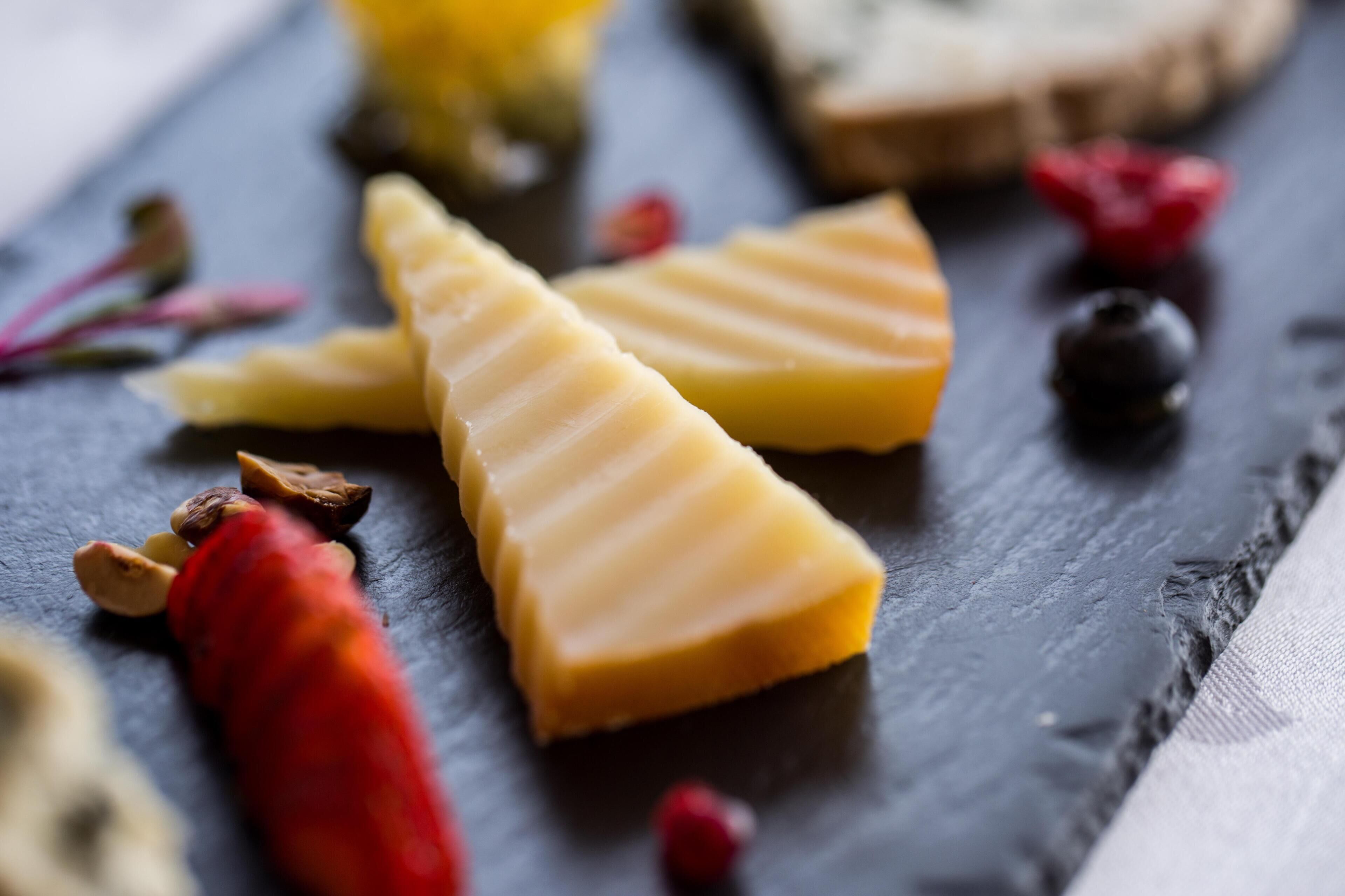 Variedad de quesos sobre una tabla de pizarra con frutos secos y frutas deshidratadas.