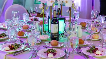 A formal dining table set with multiple plates, glasses, and a bottle of wine.
