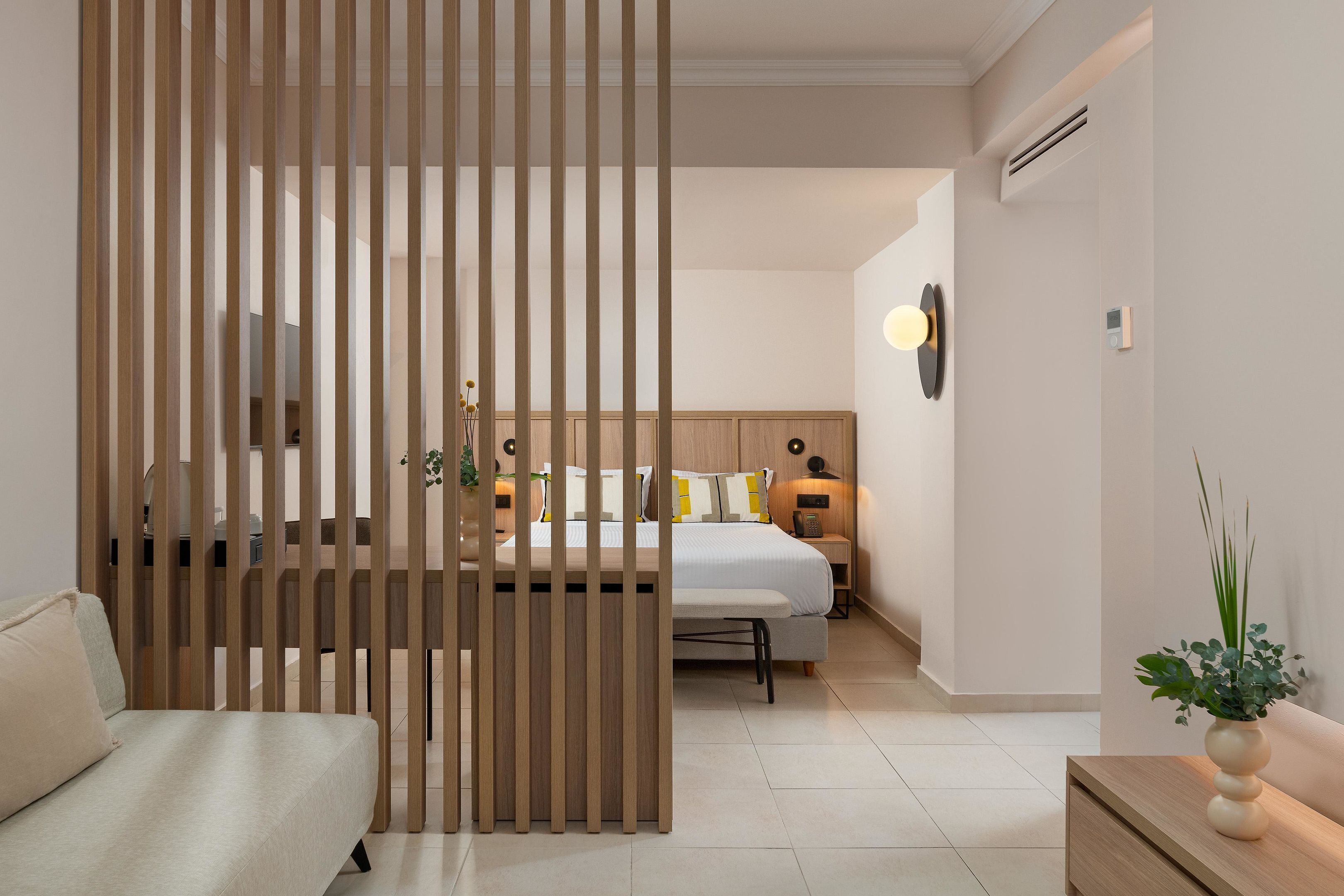 Une chambre d’hôtel avec un lit, une table de chevet, une lampe et une plante décorative.