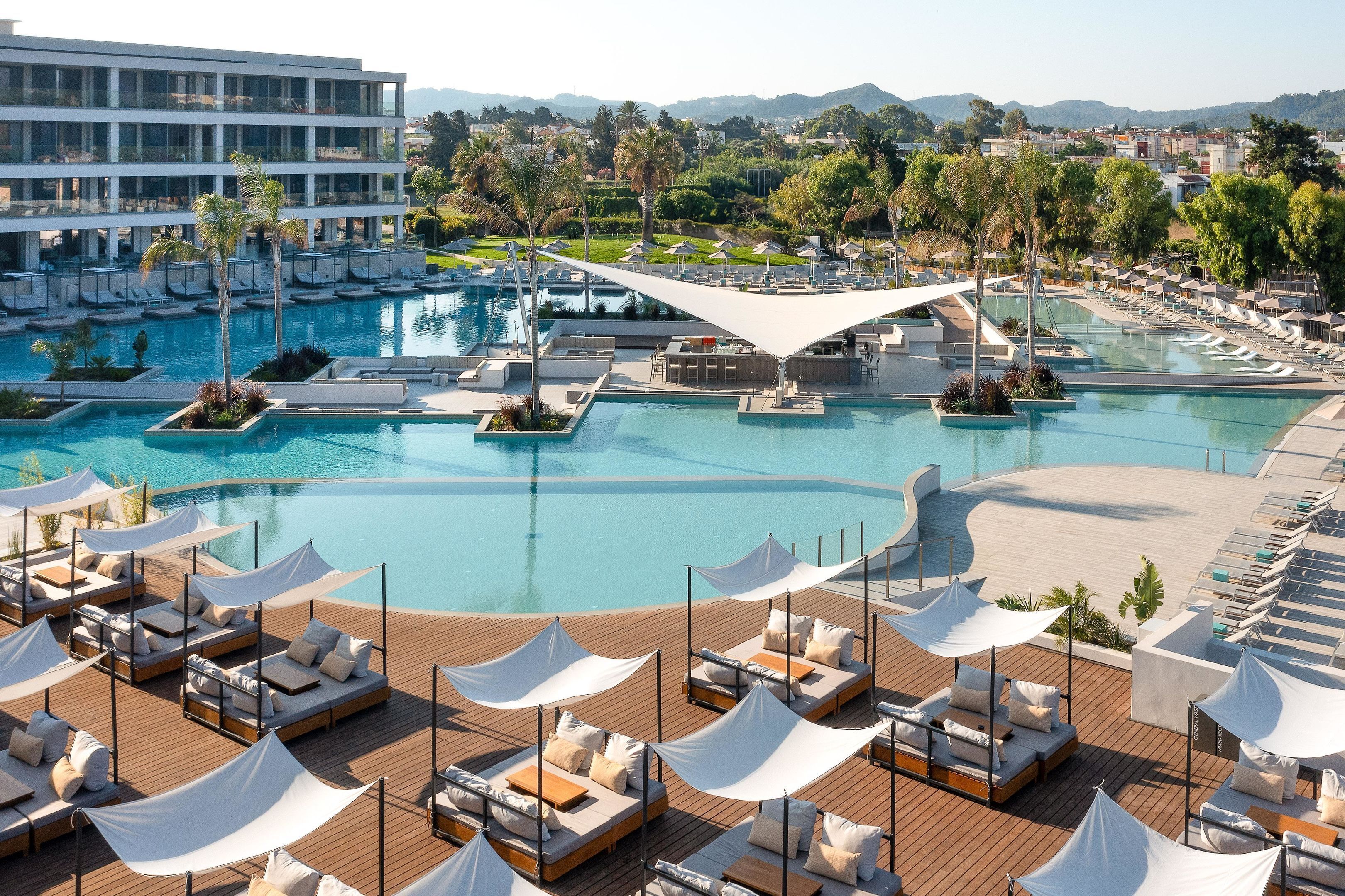 Un resort con una piscina grande, sillones de sol y vistas del paisaje circundante.