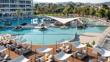Un resort con una piscina grande, sillones de sol y vistas del paisaje circundante.