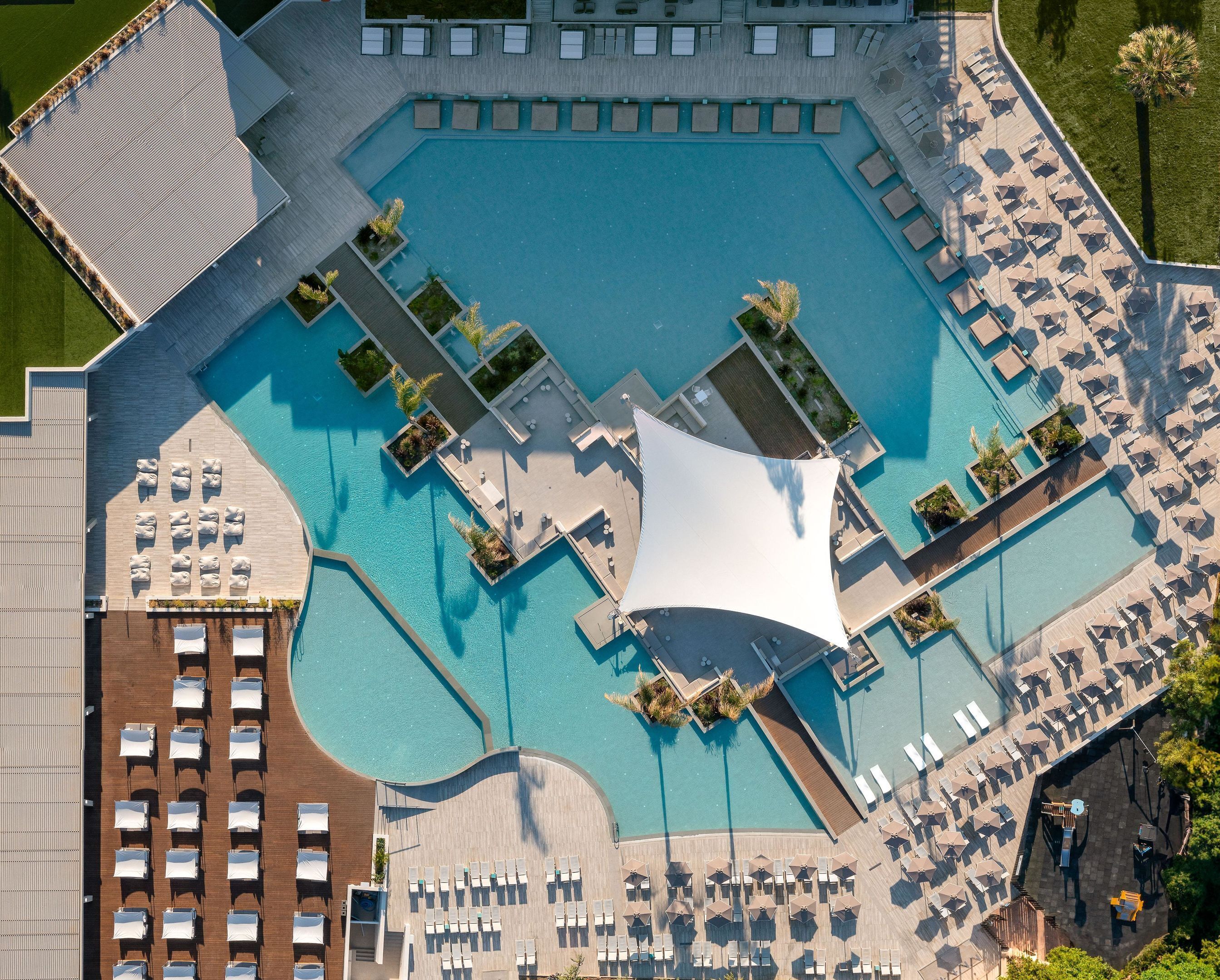 An aerial view of a resort with multiple swimming pools, sun loungers, and umbrellas.