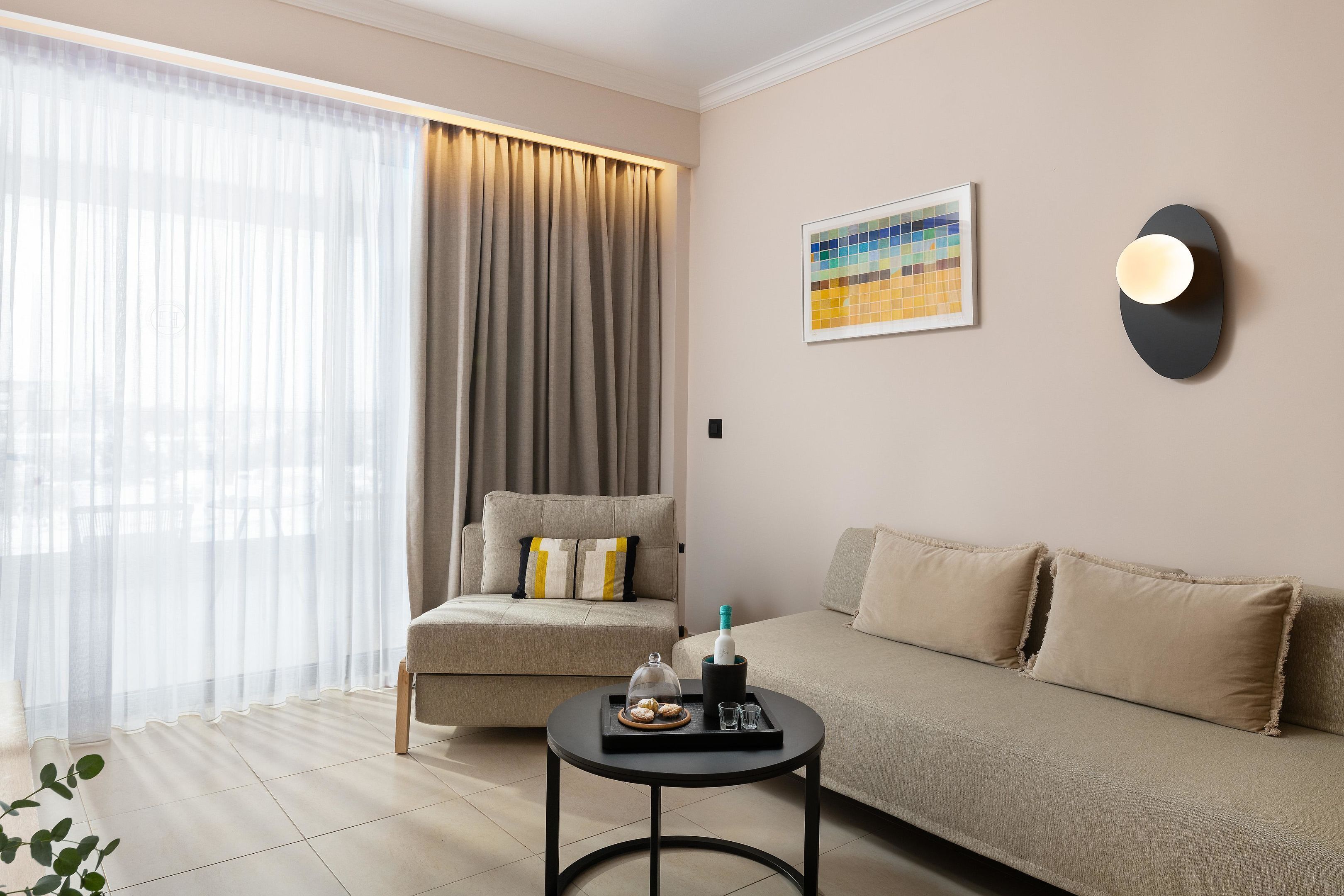 A modern living room with a sofa, a chair, a small table, and a large window with curtains.