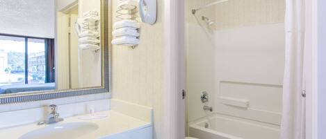 Une salle de bain équipée d’un lavabo, d’un miroir, d’un porte-serviettes et d’un espace douche.