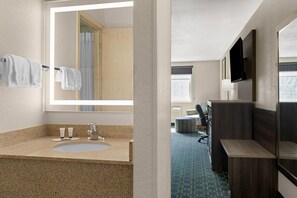A hotel bathroom with a large mirror, a sink, and a toilet. - Baymont by Wyndham Santa Fe (Santa Fe)