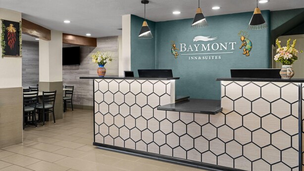 A reception desk with a logo for Baymont Inn & Suites, a flat-screen TV, and a seating area with chairs. - Baymont by Wyndham Santa Fe (Santa Fe)