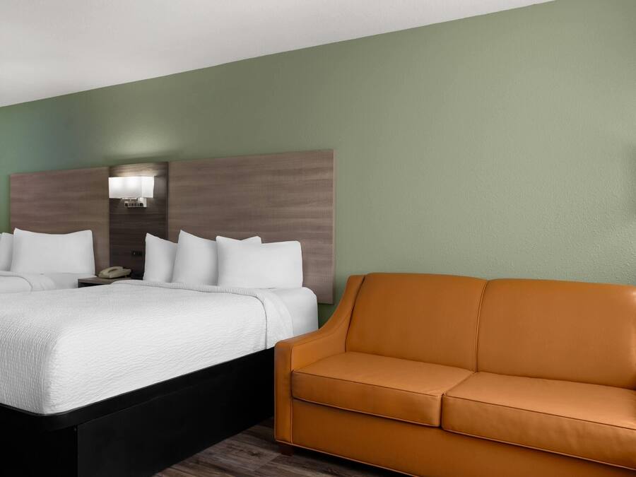 Une chambre d’hôtel comprenant un lit, un canapé, une table de chevet avec une lampe et un luminaire fixé au mur.