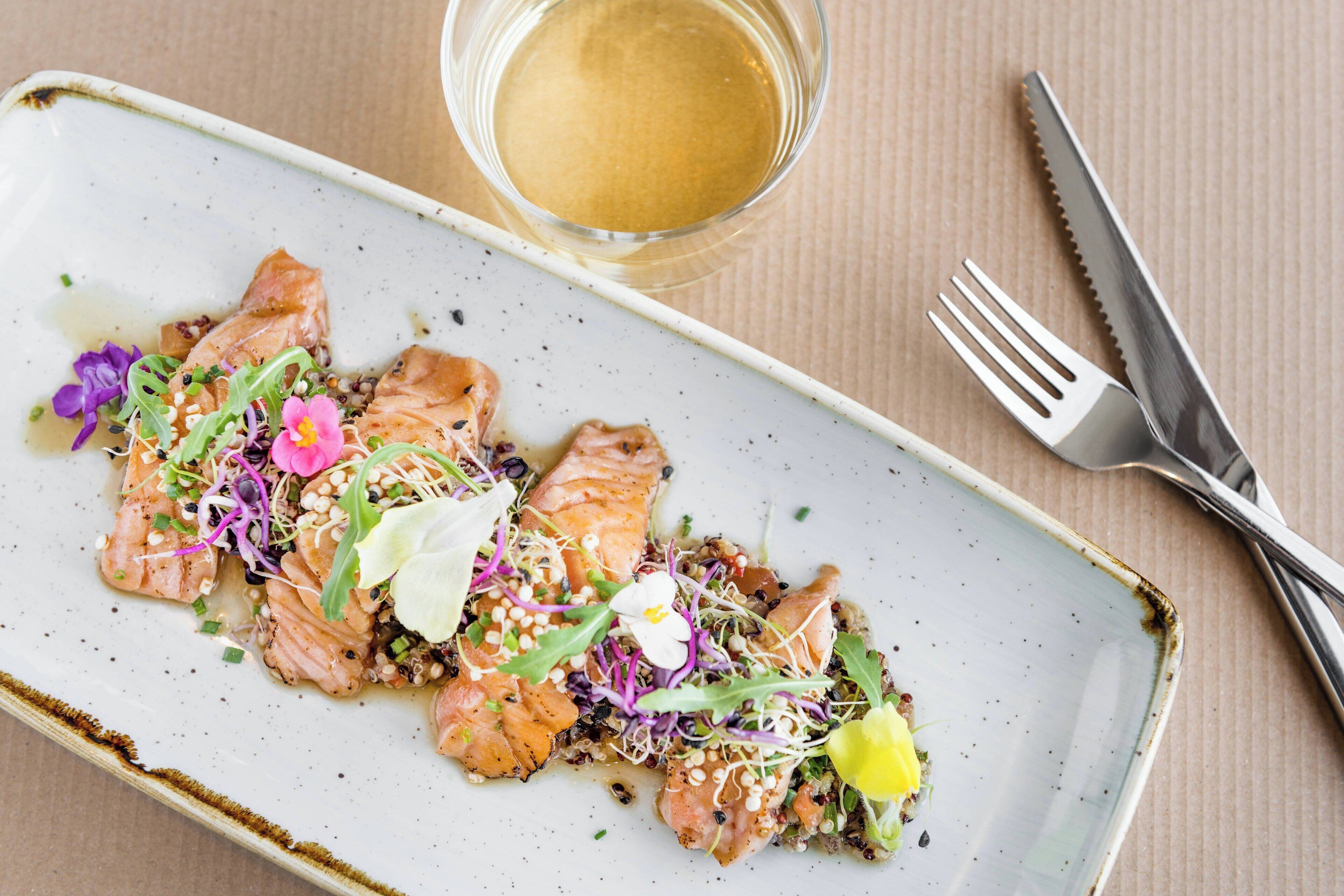 Een bord eten met zalm, groenten en bloemen.