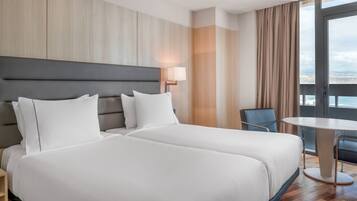 Habitación de hotel con dos camas, un escritorio y una silla.