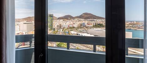 Un paisaje urbano con una montaña al fondo, visto desde un balcón con barandilla de metal.