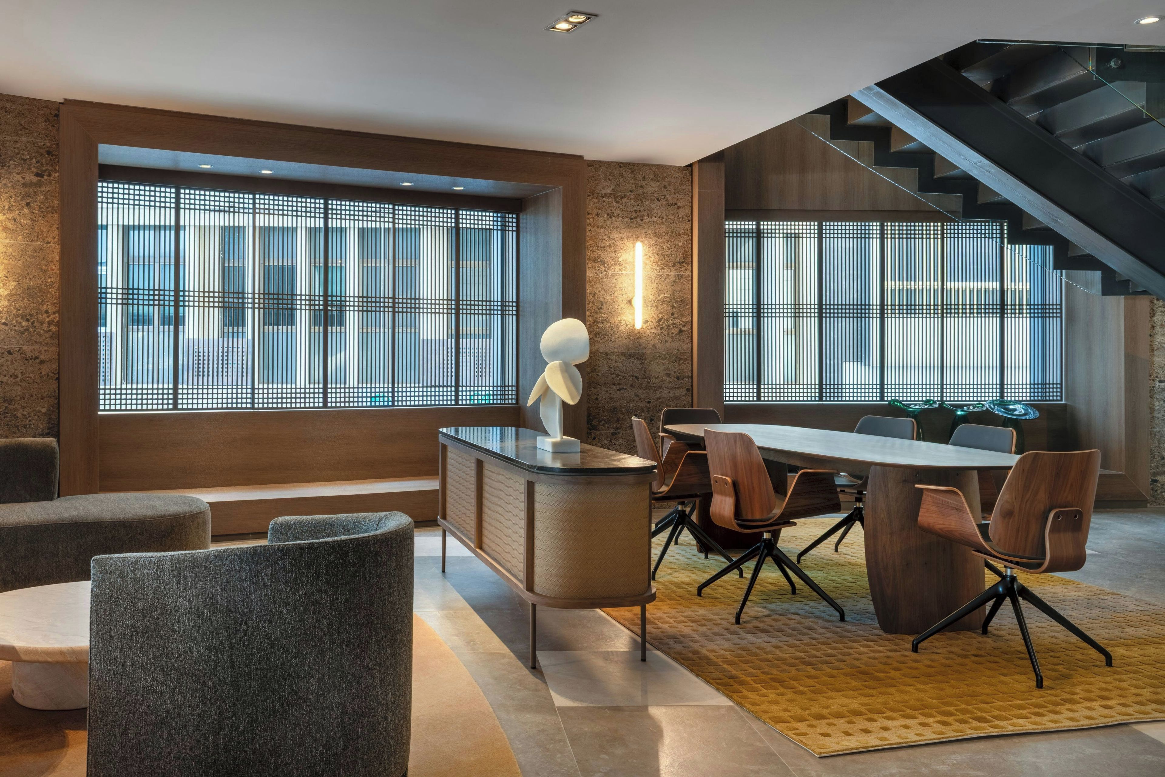 A modern interior with a dining area, a staircase, and large windows with a grid pattern.