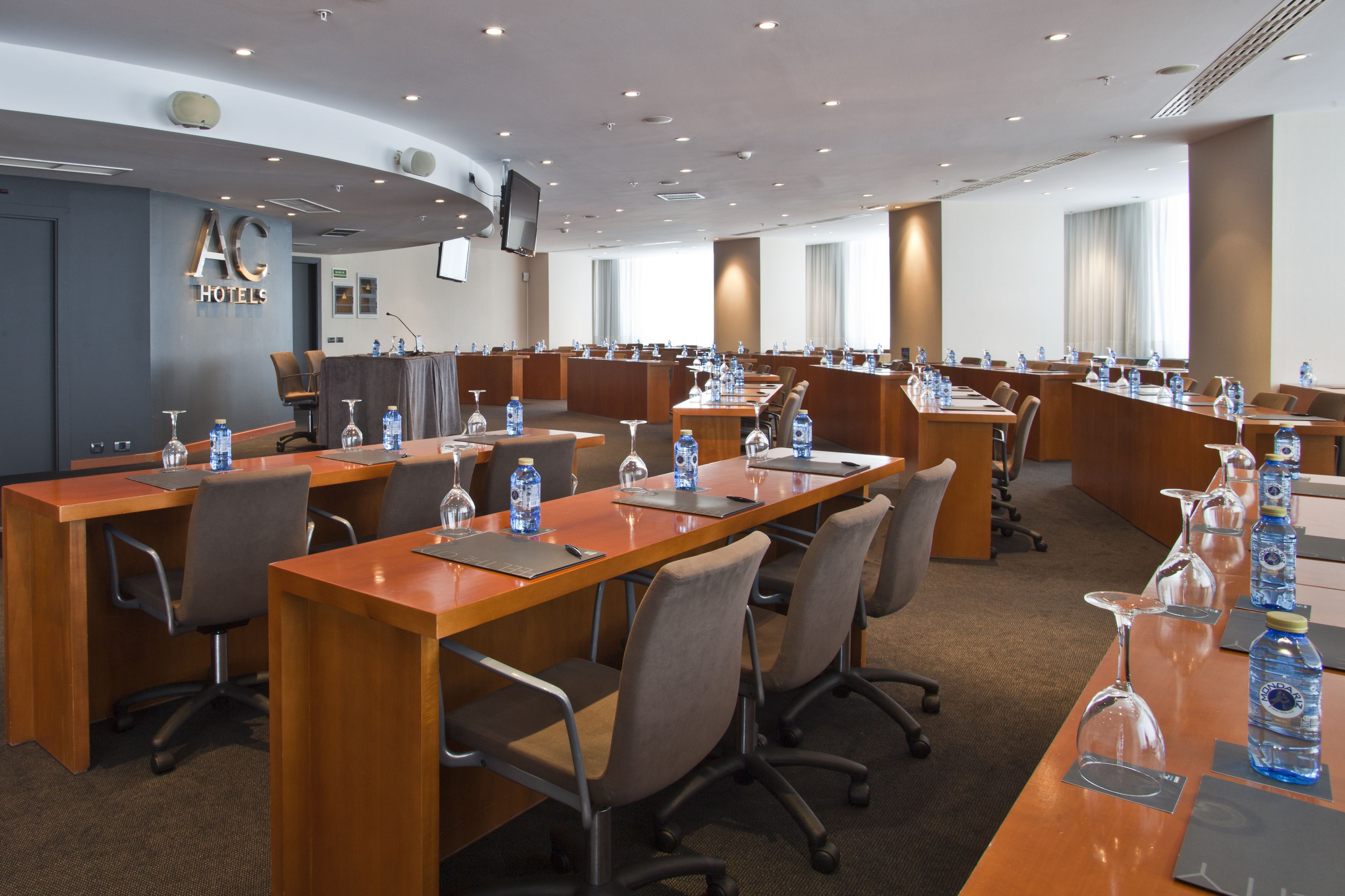 A conference room with multiple tables, chairs, and water bottles.