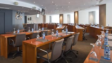 A conference room with multiple tables, chairs, and water bottles.