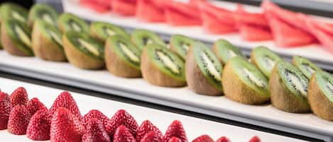 Ein reichhaltiges Buffet mit ansprechend drappierten Fruchtschnitten, darunter Erdbeeren, Kiwi und Wassermelone.