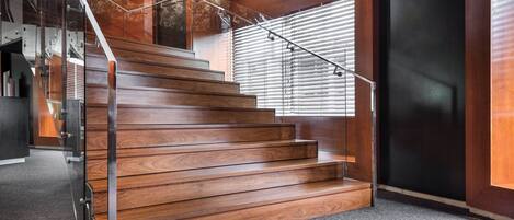 A wooden staircase with metal railings, leading to a landing with a glass door.