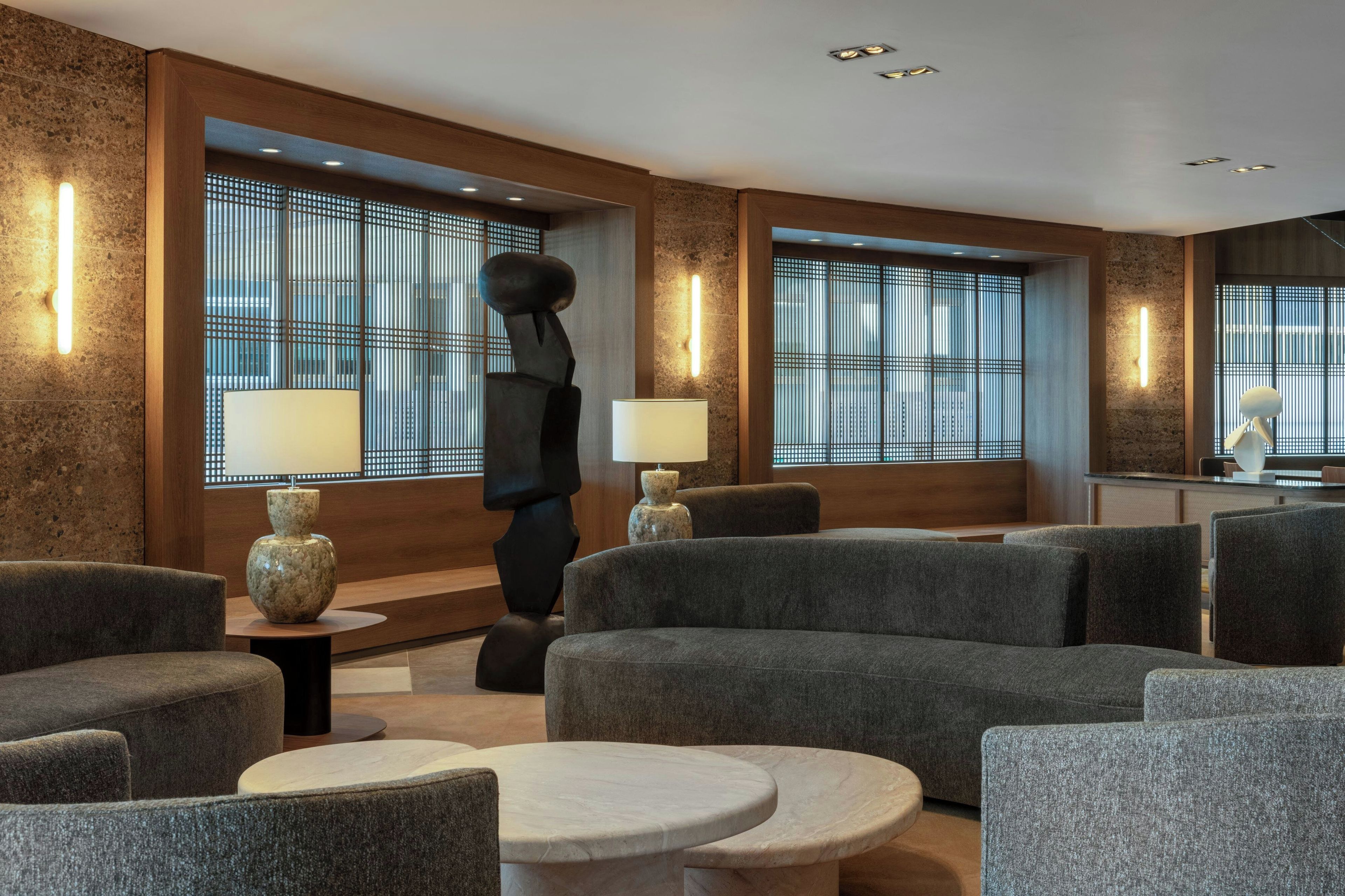 A modern lounge area with sofas, a round table, and decorative lamps.