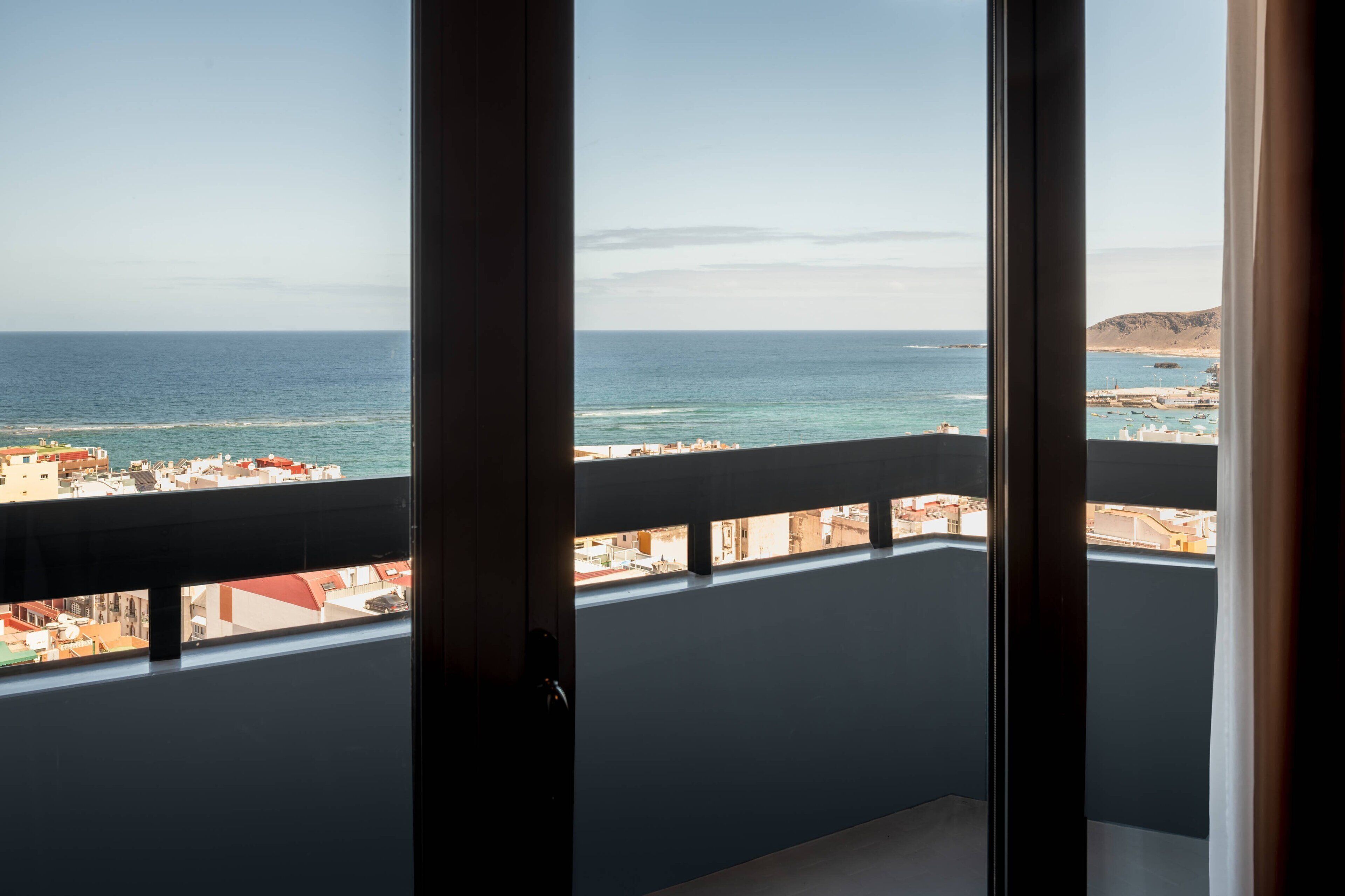 A balcony with a view of the ocean and a distant coastline.