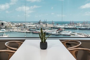 Quarto com vista para um porto, um vaso de planta e uma mesa branca.