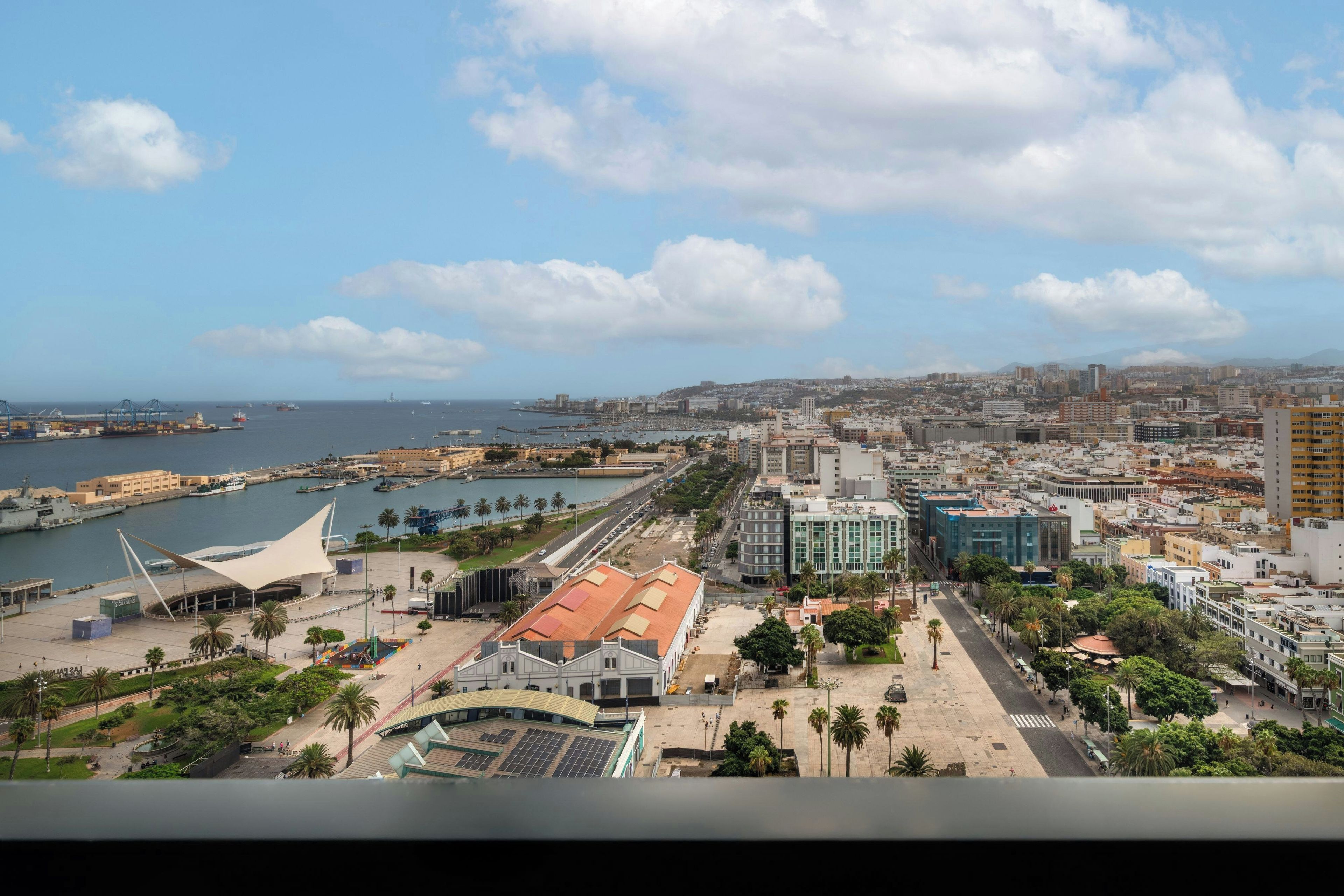 Un paysage urbain côtier avec un port de plaisance, des bâtiments modernes et une imposante structure blanche.
