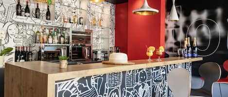 A bar area with a counter, bar stools, and a wall with a black and white abstract design.