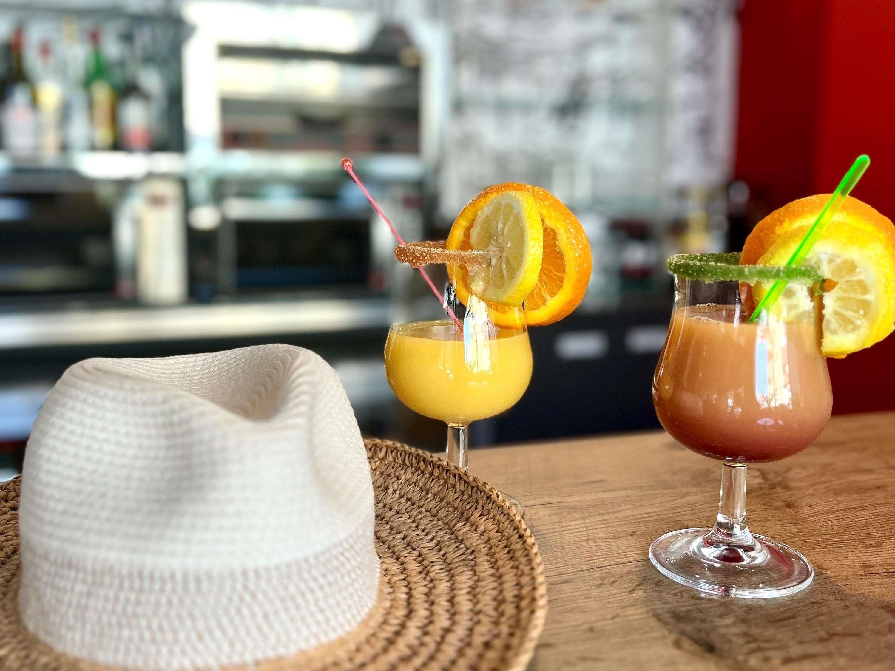 Une scène de bar avec deux boissons, un chapeau et un tapis tissé.