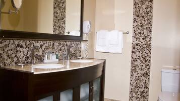 A bathroom with a double sink vanity, a large mirror, and a toilet.