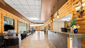 A hotel lobby with wooden paneling, a reception desk, seating area, and a large window with a view.