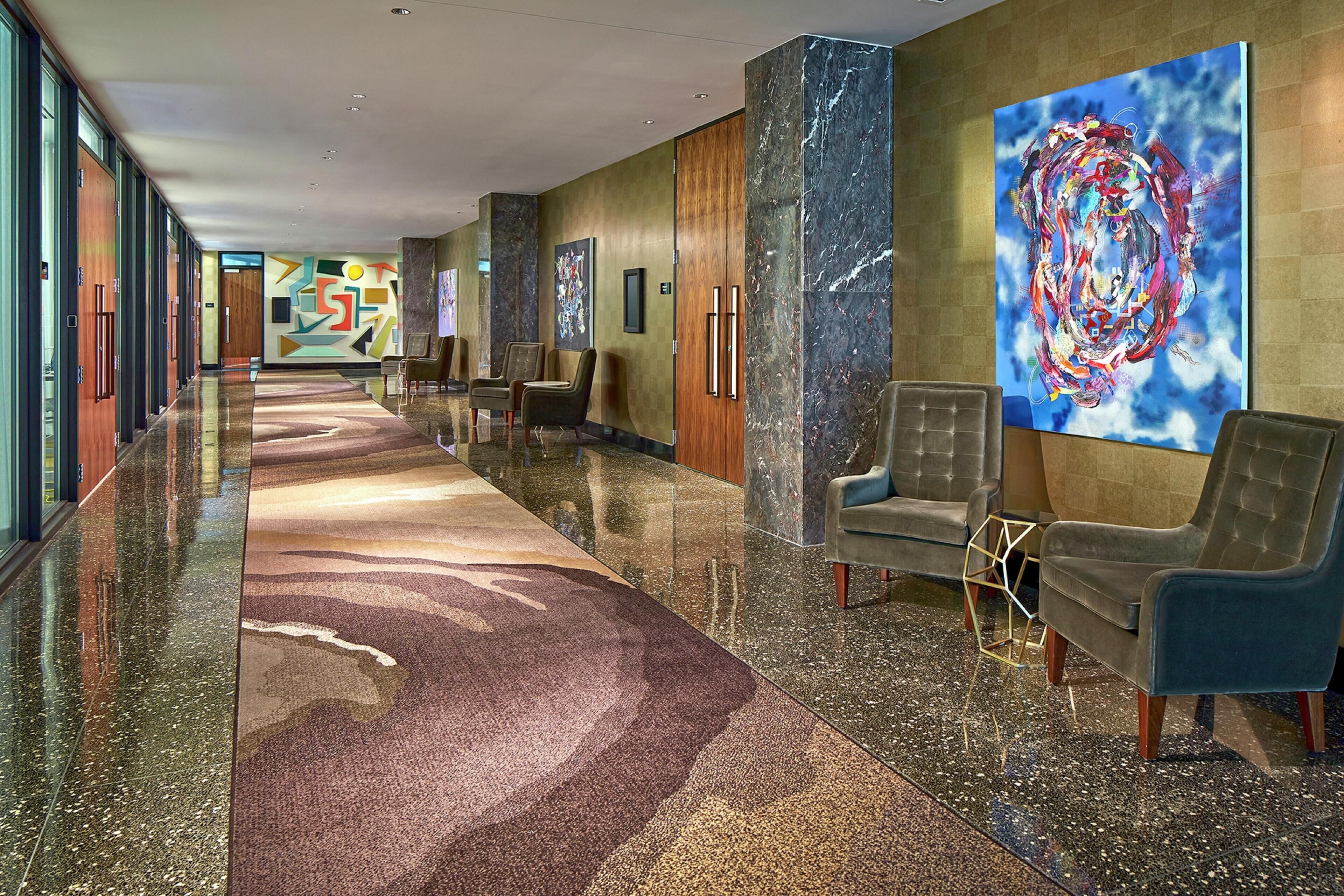 Eine Hotellobby mit einer langen Diele, einer Sitzecke und Kunstwerken an den Wänden.