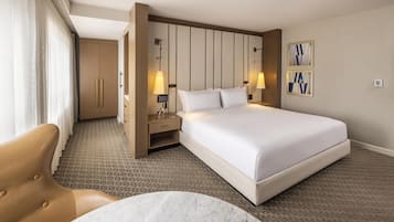 Una habitación de hotel con una cama grande, un escritorio con lámpara, una silla y una mesa de mármol.