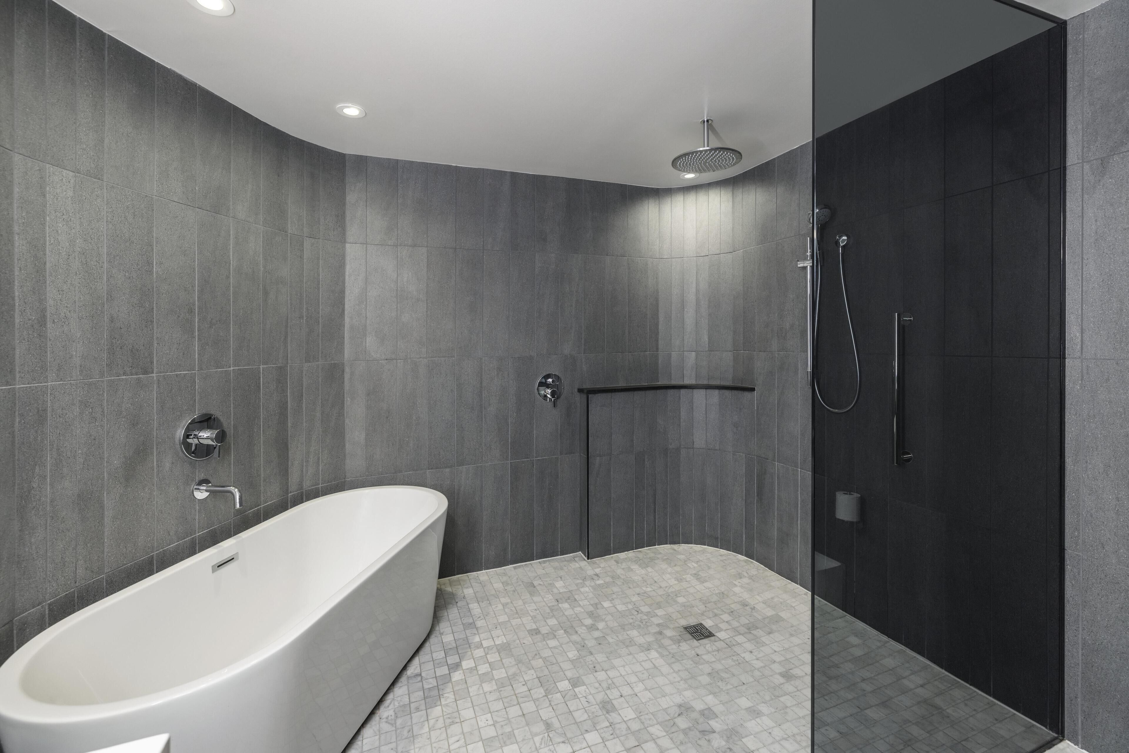 Une salle de bain moderne avec une baignoire sur pieds, une douche séparée par des parois en verre et un sol carrelé.