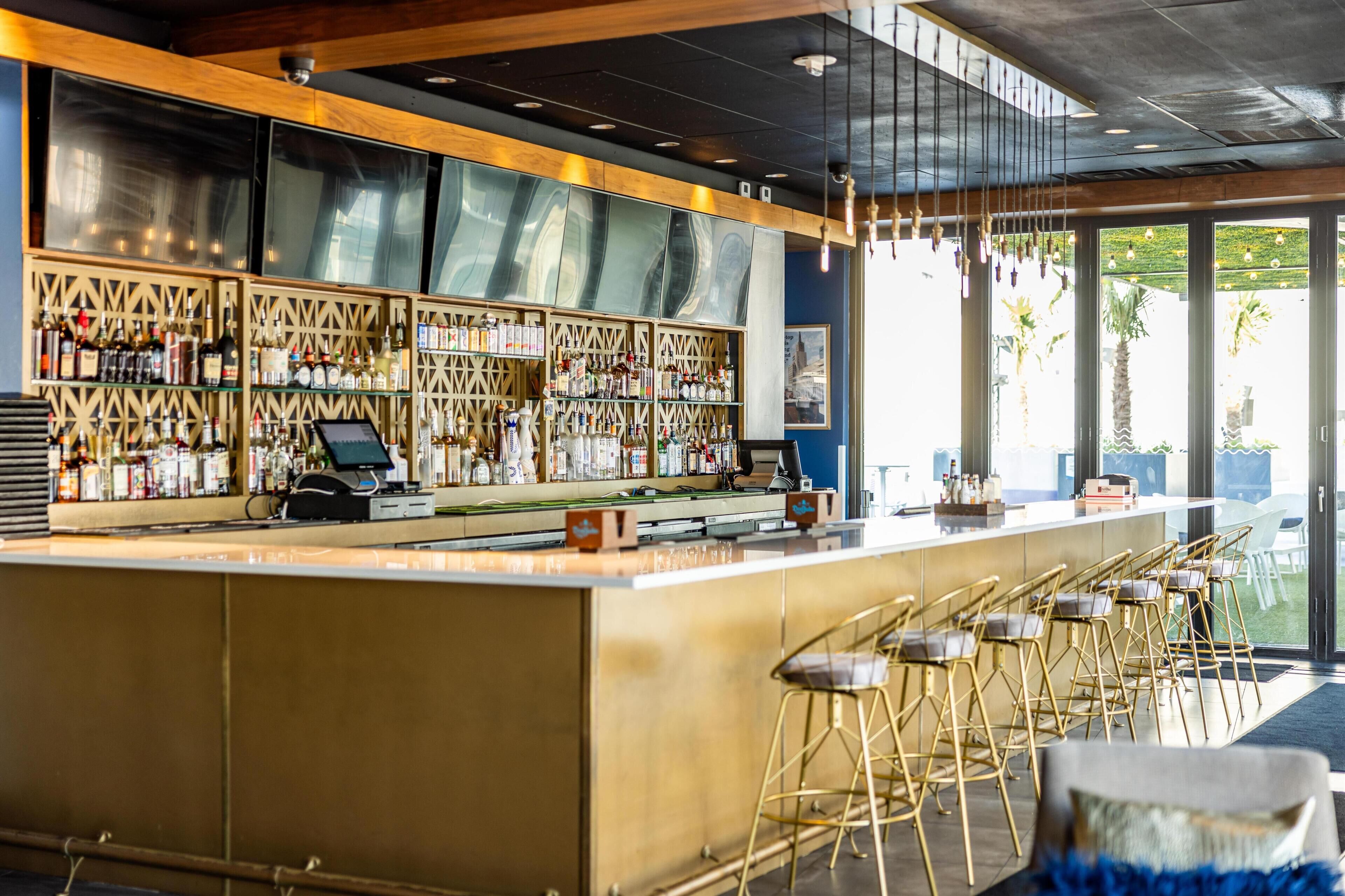 A bar area with a counter, stools, and a view of the outdoors.