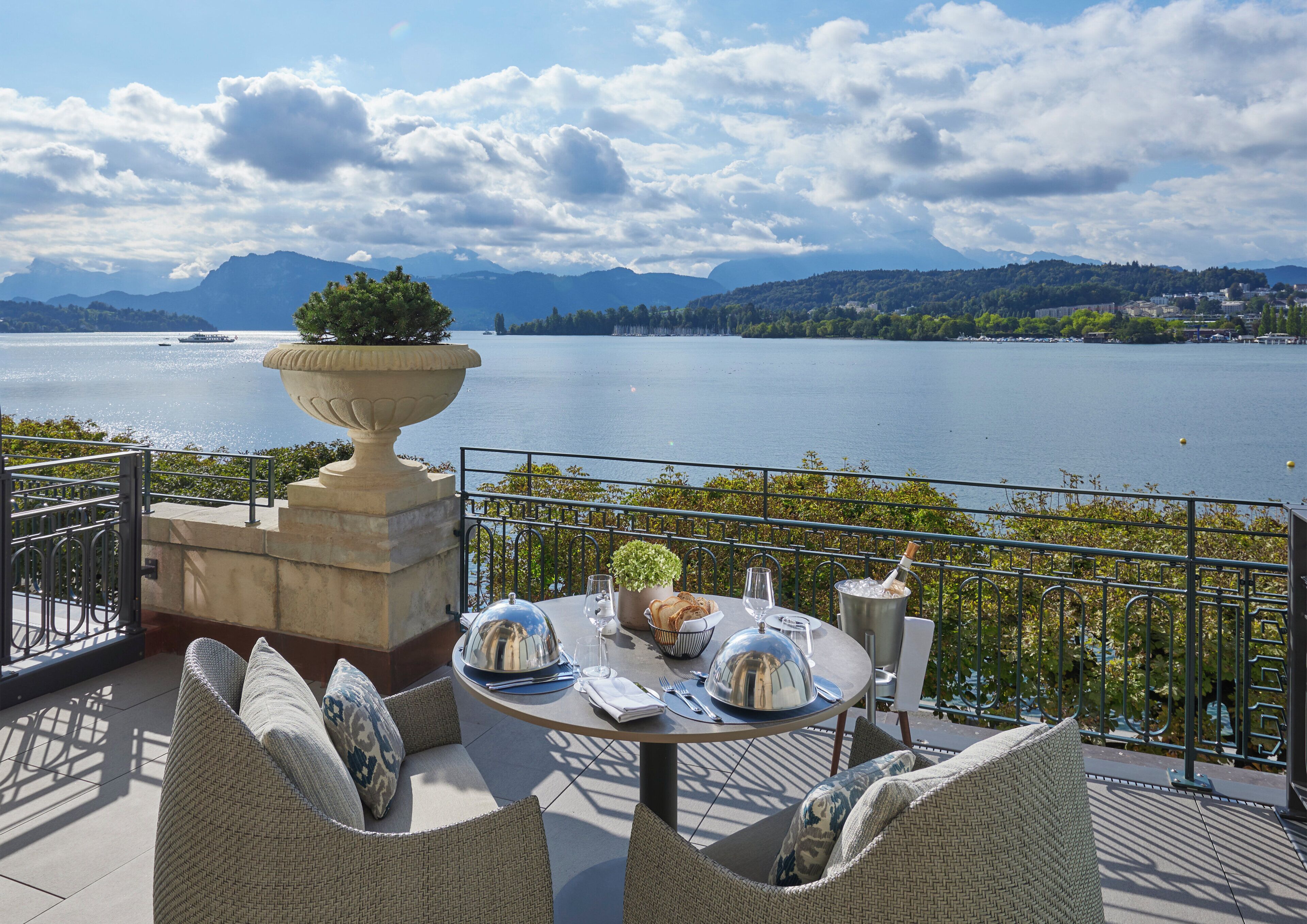 Eine Terrasse mit Esstisch, mit Blick auf einen See und Berge im Hintergrund.